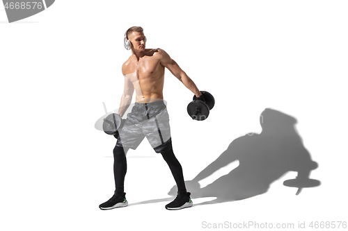 Image of Beautiful young male athlete practicing on white studio background with shadows