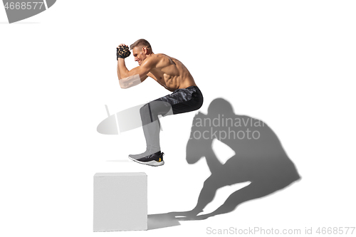 Image of Beautiful young male athlete practicing on white studio background with shadows