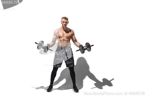 Image of Beautiful young male athlete practicing on white studio background with shadows