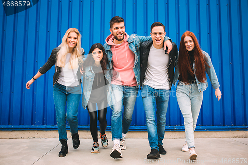 Image of Group of four young diverse friends in jeanse outfit look carefree, young and happy on city\'s streets