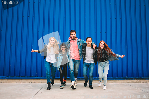 Image of Group of four young diverse friends in jeanse outfit look carefree, young and happy on city\'s streets