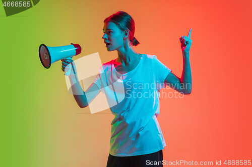 Image of Young caucasian girl\'s portrait on gradient green-orange studio background in neon light