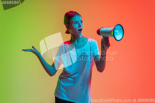 Image of Young caucasian girl\'s portrait on gradient green-orange studio background in neon light