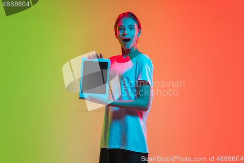 Image of Young caucasian girl\'s portrait on gradient green-orange studio background in neon light