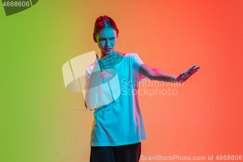 Image of Young caucasian girl\'s portrait on gradient green-orange studio background in neon light