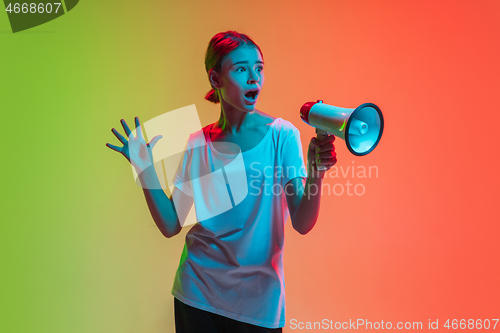 Image of Young caucasian girl\'s portrait on gradient green-orange studio background in neon light