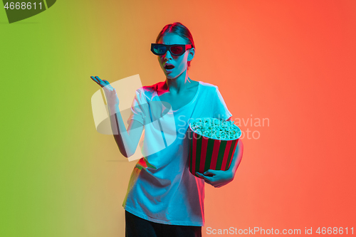 Image of Young caucasian girl\'s portrait on gradient green-orange studio background in neon light