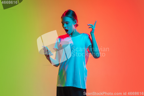 Image of Young caucasian girl\'s portrait on gradient green-orange studio background in neon light