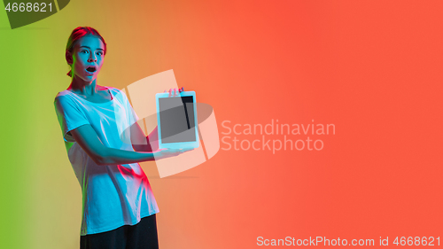 Image of Young caucasian girl\'s portrait on gradient green-orange studio background in neon light