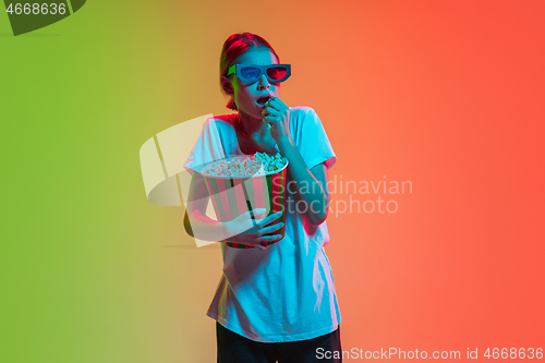 Image of Young caucasian girl\'s portrait on gradient green-orange studio background in neon light