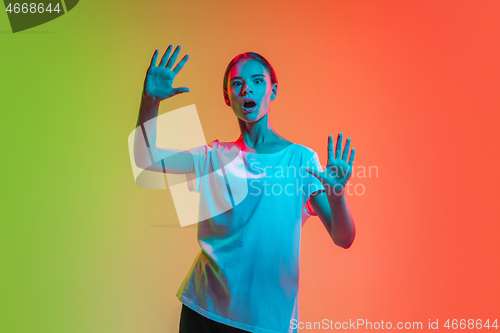 Image of Young caucasian girl\'s portrait on gradient green-orange studio background in neon light