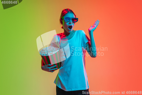 Image of Young caucasian girl\'s portrait on gradient green-orange studio background in neon light