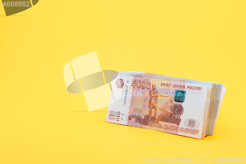 Image of A pack of five thousandth bills on a yellow background