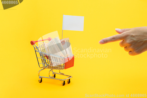 Image of Hand points to a grocery cart with a bundle of notes and a white flag for inscription