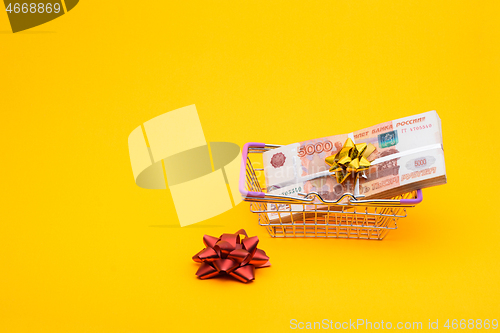 Image of In the grocery basket is a bundle of five thousandth bills, next to it is a red bow