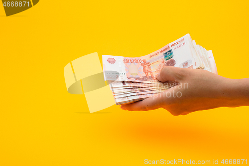 Image of In hand a pack of five thousandth Russian rubles, yellow background