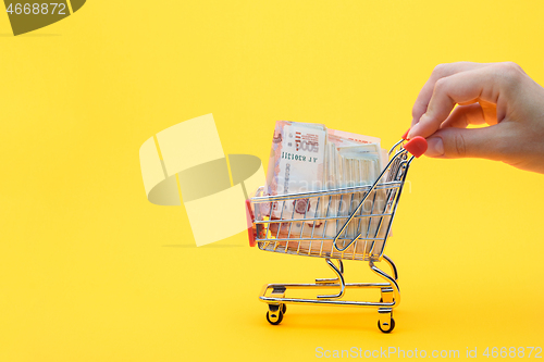 Image of Hand carries a grocery cart with a pack of five thousandth Russian rubles