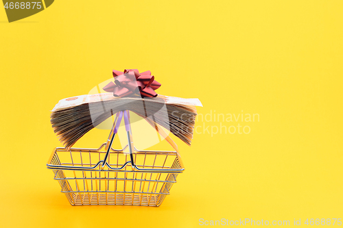 Image of On the handles of the grocery cart lies a bundle of notes packed with gift ribbon and a red bow
