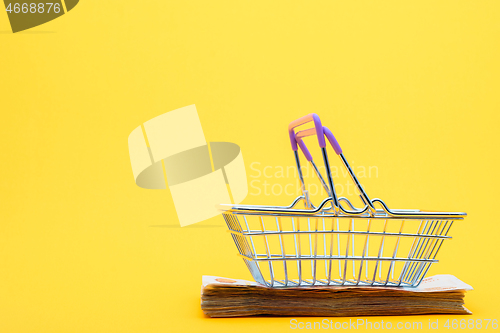 Image of On a bundle of notes lies an empty grocery basket with raised handles