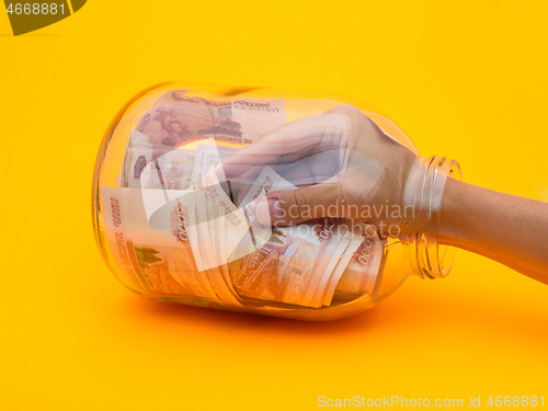 Image of Hand climbed into a glass jar full of five thousandth bills