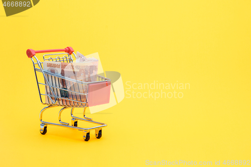 Image of In the grocery cart lies a pack of five thousandth Russian bills, yellow background