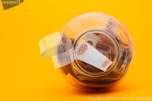 Image of Five thousandth notes are packed in a glass jar lying on its side