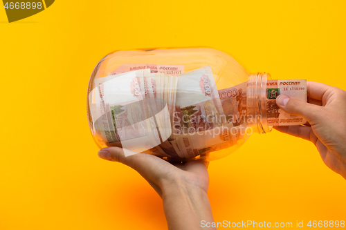 Image of Hands pull a five thousandth bill out of a glass jar