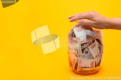 Image of A hand covered the neck of a three-liter jar filled with five thousandth bills