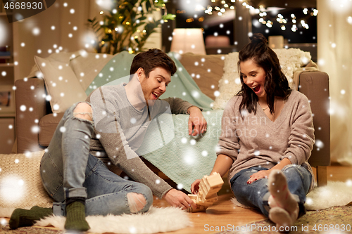 Image of happy couple playing block-stacking game at home