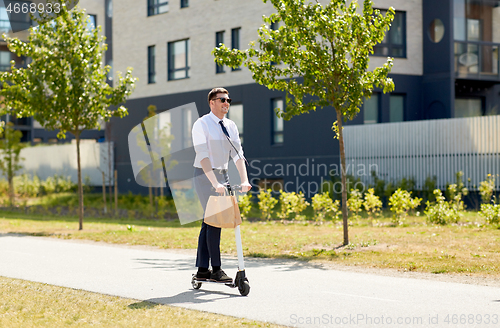 Image of businessman with lunch in paper bag riding scooter