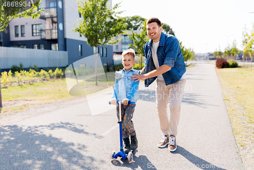 Image of happy father and little son riding scooter in city