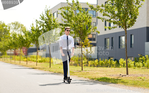 Image of young businessman riding electric scooter outdoors