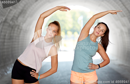 Image of women with fitness trackers stretching outdoors