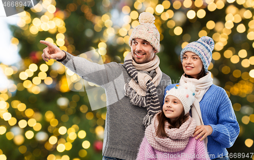 Image of happy family in winter hats over christmas lights