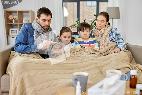 Image of family with ill children having fever at home