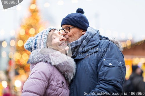 Image of happy senior couple kissing at christmas market