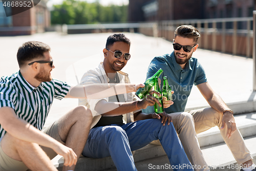 Image of happy male friends drinking beer on street