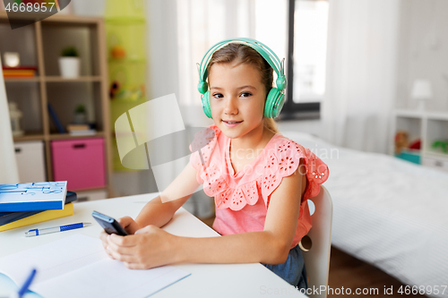 Image of girl in headphones listening to music on cellphone