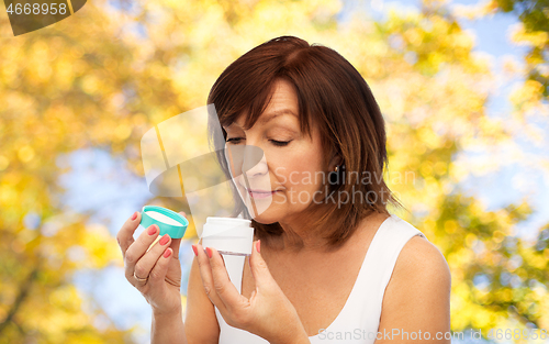 Image of senior woman with cream jar over autumn trees