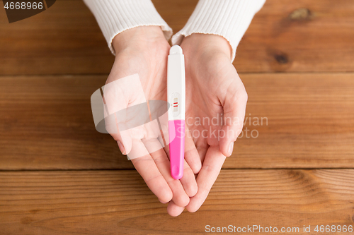 Image of woman hands holding positive pregnancy test