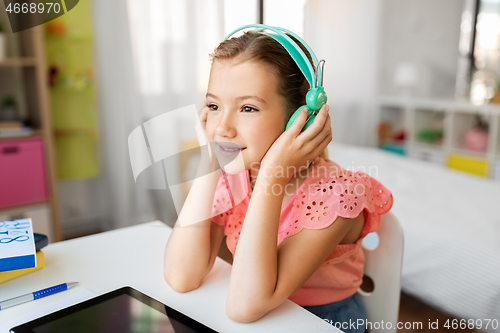 Image of girl in headphones with tablet computer at home