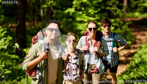 Image of group of friends with backpacks hiking in forest