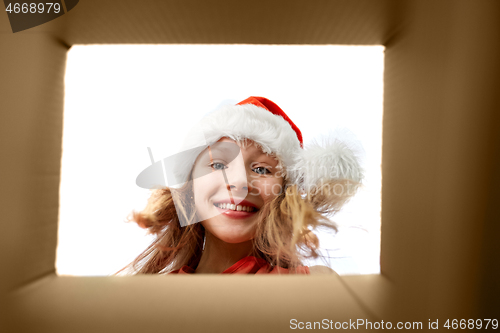 Image of girl in santa hat looking into christmas gift box
