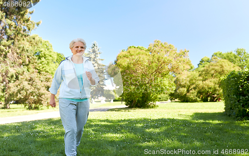 Image of senior woman running along summer park