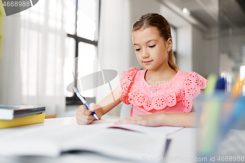 Image of student girl with book writing to notebook at home