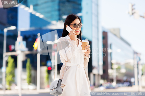 Image of smiling asian woman calling on smartphone in city