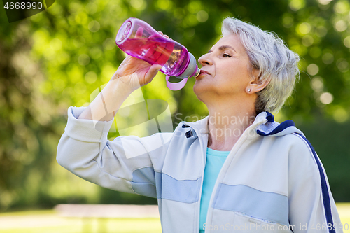 Image of senior woman drinks water after exercising in park