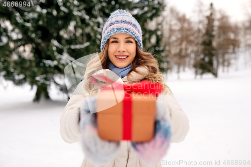 Image of happy young woman with christmas gift in winter