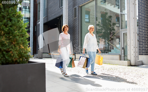 Image of senior women with shopping bags walking in city