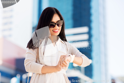 Image of woman looking at wristwatch or smart watch in city